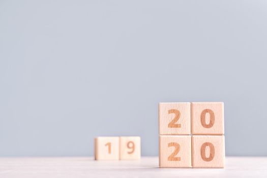 Abstract 2020 & 2019 New year countdown design concept - wood blocks cubes on wooden table and low saturation blue background, close up, copy space.