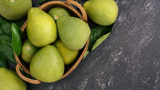 Fresh peeled pomelo, pummelo, grapefruit, shaddock on dark background in bamboo basket. Autumn seasonal fruit, top view, flat lay, tabletop shot.