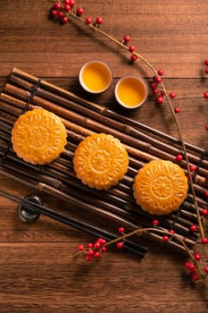 Chinese traditional pastry Moon cake Mooncake with tea cups on bamboo serving tray on wooden background for Mid-Autumn Festival, top view, flat lay.