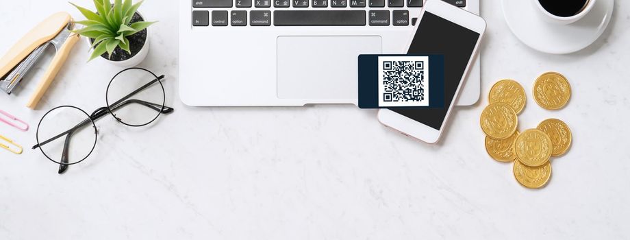 Online payment with QR code concept, virtual credit card, smart phone on office laptop desk on clean marble table background, top view, flat lay