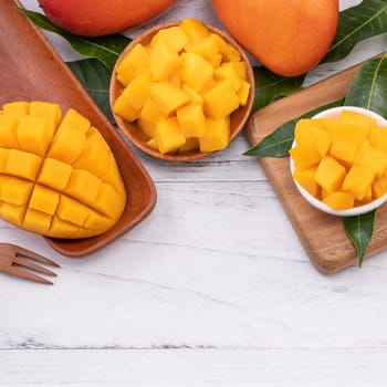 Fresh chopped mango on a tray and bright rustic wooden background. Tropical summer fruit design concept, close up, macro, copy space.