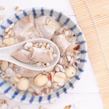 Tasty Four Tonics Herb Flavor Soup, Taiwanese traditional food with herbs, pork intestines on white wooden table, close up, flat lay, top view