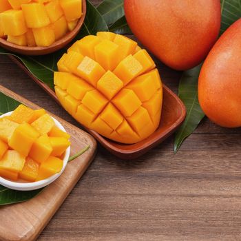 Fresh mango,beautiful chopped fruit with green leaves on dark wooden table background. Tropical fruit design concept. Flat lay. Top view. Copy space