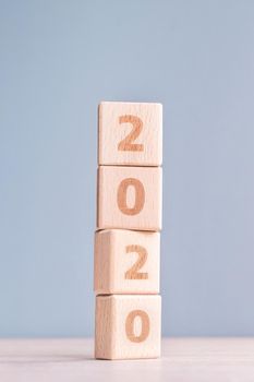 Abstract 2020, 2019 New year target plan design concept - wood blocks cubes on wooden table and pastel blue background, close up, blank copy space.