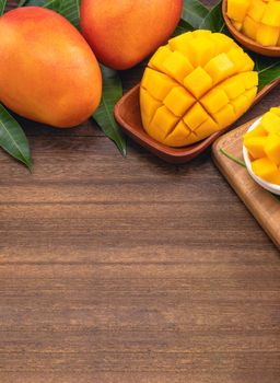 Fresh mango,beautiful chopped fruit with green leaves on dark wooden table background. Tropical fruit design concept. Flat lay. Top view. Copy space