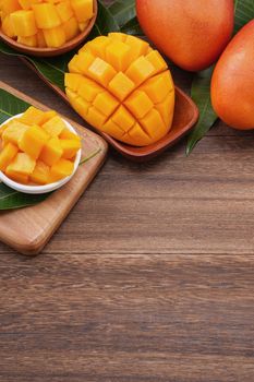 Fresh mango, beautiful chopped fruit with green leaves on dark wooden table background. Tropical fruit design concept. Flat lay. Top view. Copy space