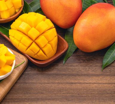 Fresh mango,beautiful chopped fruit with green leaves on dark wooden table background. Tropical fruit design concept. Flat lay. Top view. Copy space