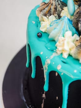 frosted black painted cup cake with blue turquoise dripping and colored handmade meringue topping studio white isolated background