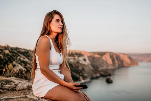 Woman travel sea. Young Happy woman in a long red dress posing on a beach near the sea on background of volcanic rocks, like in Iceland, sharing travel adventure journey