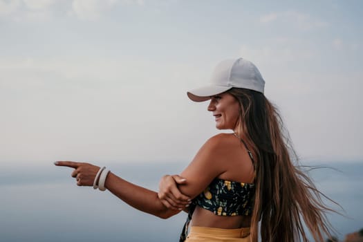 Woman travel sea. Happy tourist taking picture outdoors for memories. Woman traveler looks at the edge of the cliff on the sea bay of mountains, sharing travel adventure journey.