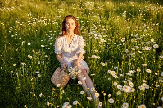 a beautiful woman in a light dress sits in a field in chamomile flowers. High quality photo