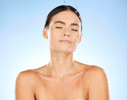 Shower, water and woman cleaning skin for beauty and cosmetic skincare isolated in a studio blue background. Facial, splash and female model washing as body care for hygiene, dermatology and wellness.