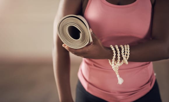 Ready to take on the day. an unrecognizable woman standing alone and holding her yoga mat before an indoor yoga session