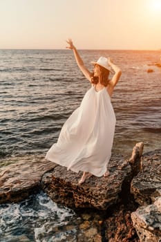 woman sea sunset. A woman in a dress, hat and with a straw bag is standing on the beach enjoying the sea. Happy summer holidays.