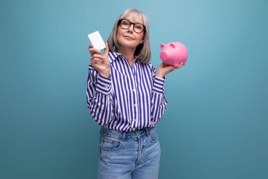 social protection. 60s middle aged woman with gray hair holding a piggy bank against a bright studio background.