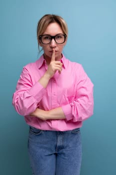young smart european office worker woman dressed in a pink shirt and glasses keeps a secret.