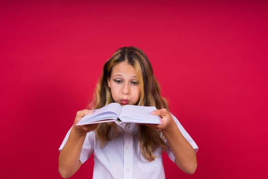 Portrait of a positive little girl with notebook, looks smiling at camera, child doing homework