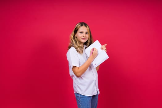 Portrait of a positive little girl with notebook, looks smiling at camera, child doing homework