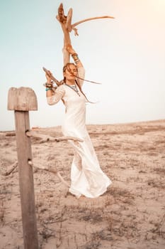 woman sea white dress. Model in boho style in a white long dress and silver jewelry on the beach. Her hair is braided, and there are many bracelets on her arms