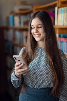 Portrait of female smiling student chatting with a friend on modern gadget