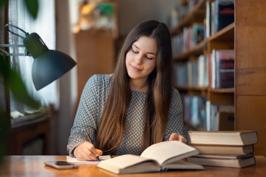 Confident woman sitting at the table and writing notes for research report, educational concept