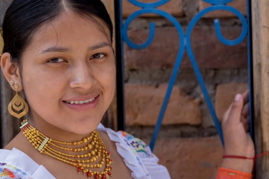 closeup with copy space of beautiful indigenous girl with dress from the native culture of ecuador next to a blue fence. High quality photo