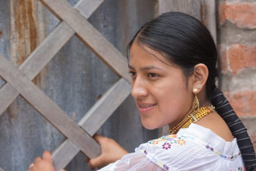 indigenous woman in profile attached to a wooden fence smiling with her traditional hair and dress of her culture. High quality photo