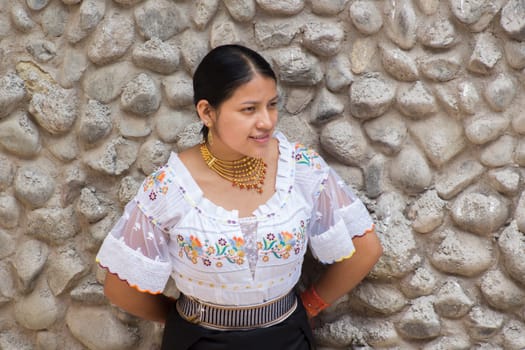 indigenous girl leaning on a wall made of stones in the amazon in traditional dress of her culture. High quality photo