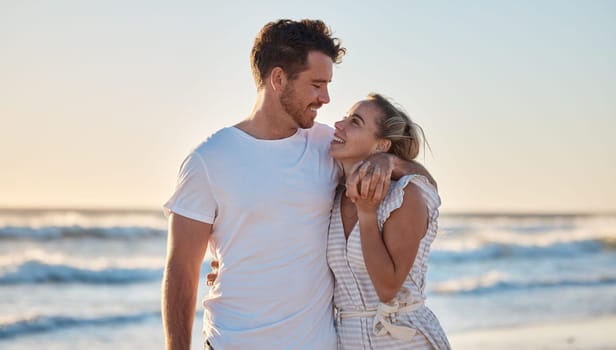 Sunset beach, love and summer with a couple hug on the sand by the sea or ocean while on holiday together. Happy, smile and romance with man and woman bonding while on travel vacation or break at sea.