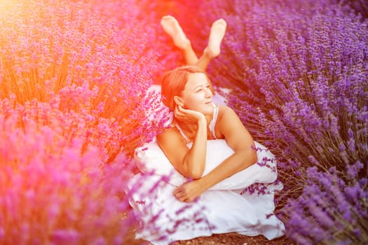 Woman lavender field. A middle-aged woman lies in a lavender field and enjoys aromatherapy. Aromatherapy concept, lavender oil, photo session in lavender.