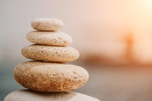 Pyramid stones on the seashore with warm sunset on the sea background. Happy holidays. Pebble beach, calm sea, travel destination. Concept of happy vacation on the sea, meditation, spa, calmness.