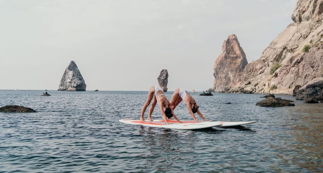 Woman sup yoga. Middle age sporty woman practising yoga pilates on paddle sup surfboard. Female stretching doing workout on sea water. Modern individual hipster outdoor summer sport activity