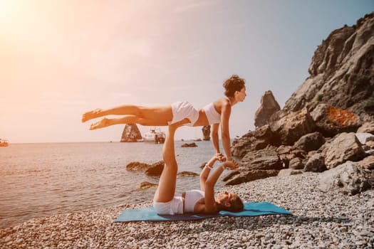 Woman sea yoga. Back view of free calm happy satisfied woman with long hair standing on top rock with yoga position against of sky by the sea. Healthy lifestyle outdoors in nature, fitness concept.