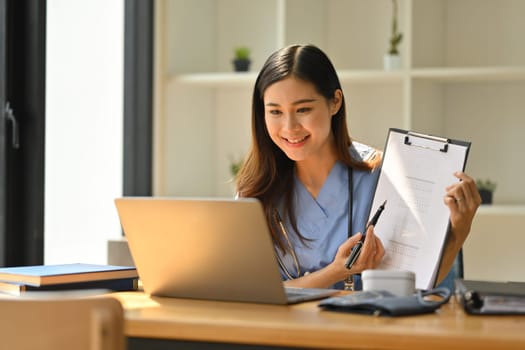 Smiling female doctor having online consultation with patient on laptop in clinic. Tele medical, healthcare and technology.