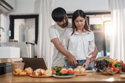 Happy couple cooking together and healthy eating concept - couple cooking food at home kitchen.