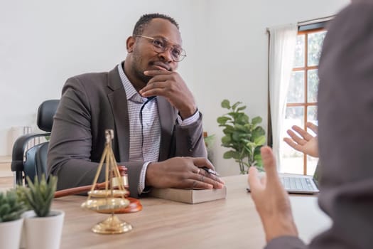 Lawyer having a discussion with a new client. Young male attorney at office desk, sharing legal advice, explaining inheritance process, trying to help. Law consultation concept.