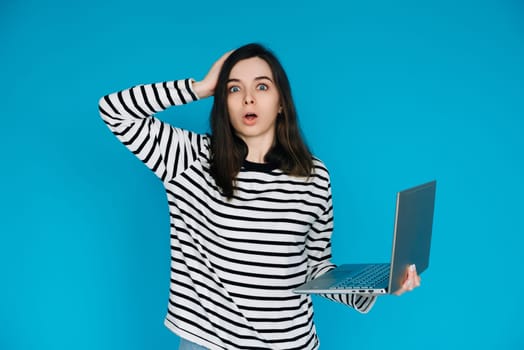 Emotional Woman in Striped Sweater Reacting to Bad News on Laptop - Conceptual Image of Sadness, Disappointment, and Technology - Isolated Blue Background with Copy Space - Perfect for Emotional,