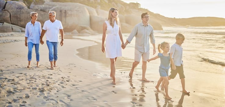Family generations, walking and beach with sunset for men, women and children with love on holiday. Parents, grandparents and kids by ocean, holding hands and bond on summer vacation with solidarity.