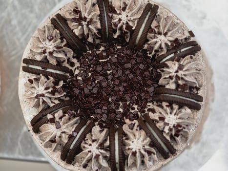 preparing brown frosted icing cup cake with cookies on top in the kitchen
