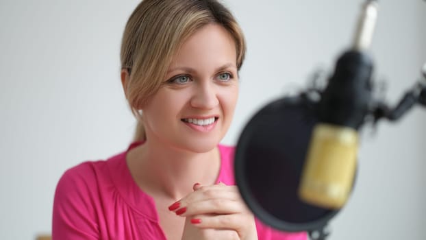 Woman radio presenter speaking into microphone in recording studio. Work on radio concept