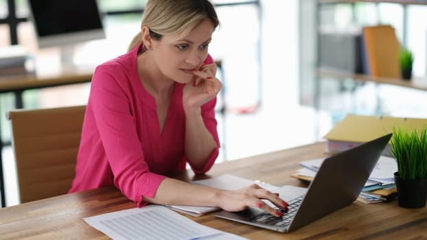 Businesswoman worried and biting her nails in front of laptop screen. Bad habits and stress at work concept