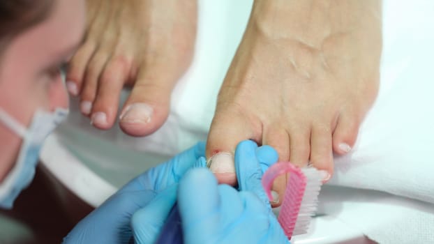 Podiatrist making professional pedicure of toe nails in beauty salon closeup. Beauty service concept