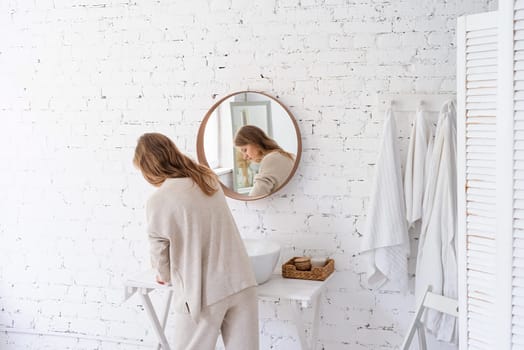 Woman looking at the mirror, making up in the morning. young millennial woman doing her morning routine at the bedroom