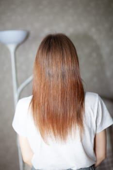 A girl with long, straight and beautiful brown hair. Hair care at home. Hair regrowth after hair coloring with henna.