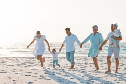 Big family, holding hands and walking on beach for holiday weekend or vacation with mockup space. Grandparents, parents and kids on a ocean walk together for fun bonding or quality time in nature.