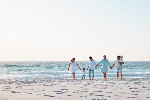 Big family, holding hands and walking on beach with mockup space for holiday weekend or vacation. Grandparents, parents and kids on a ocean walk together for fun bonding or quality time in nature.