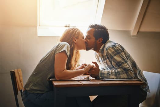 Couple, love kiss and holding hands at restaurant, intimacy or bonding together at table. Valentines day, romance diversity and affection, kissing and care of man and woman enjoying date time at cafe.