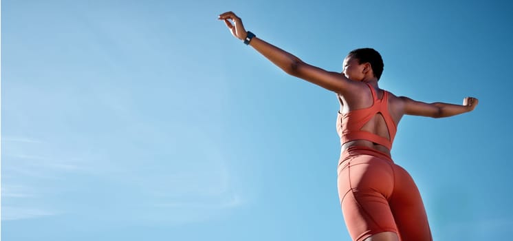 Woman, arms up or fitness success on blue sky background in workout, training or exercise goals for healthcare or cardiovascular wellness. Low angle runner, sports athlete or hands raised with mockup.