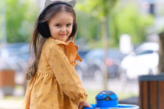 Happy little girl is playing on the playground in the park.