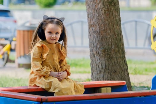 Portrait of a four-year-old girl sitting on a park bench.